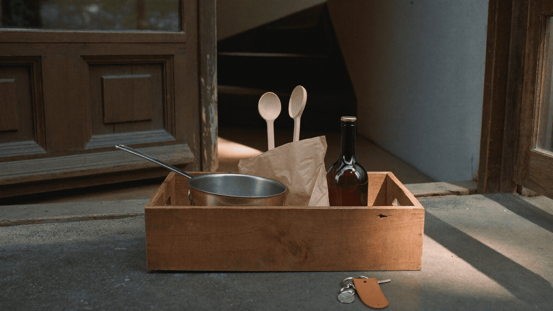 Première cuisine dans un appartement suisse le jour du déménagement: une poêle neuve, des pâtes, du riz et de l’huile sur le plan de travail, des cartons à moitié défaits derrière.