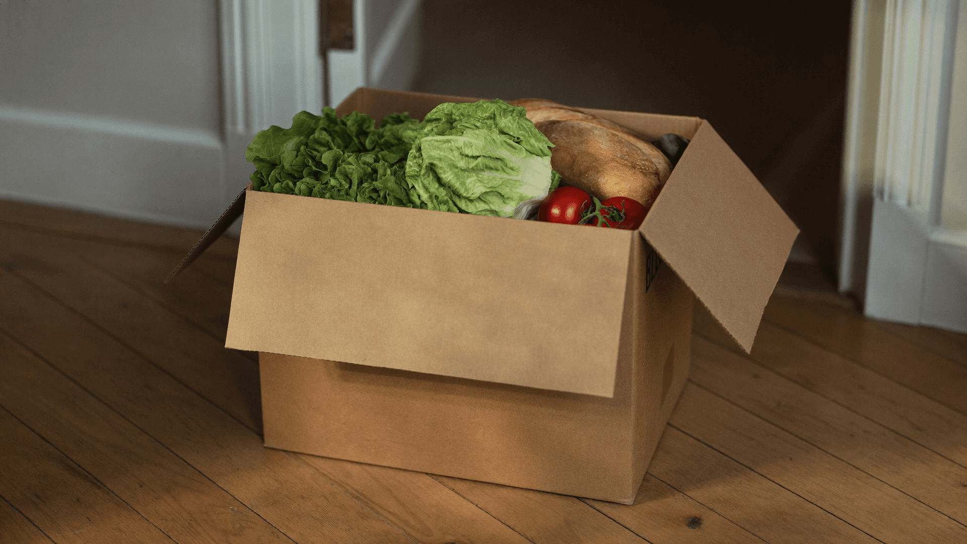 Une commande de courses remise à la porte d'un appartement suisse, avec sacs isothermes et caisses de livraison