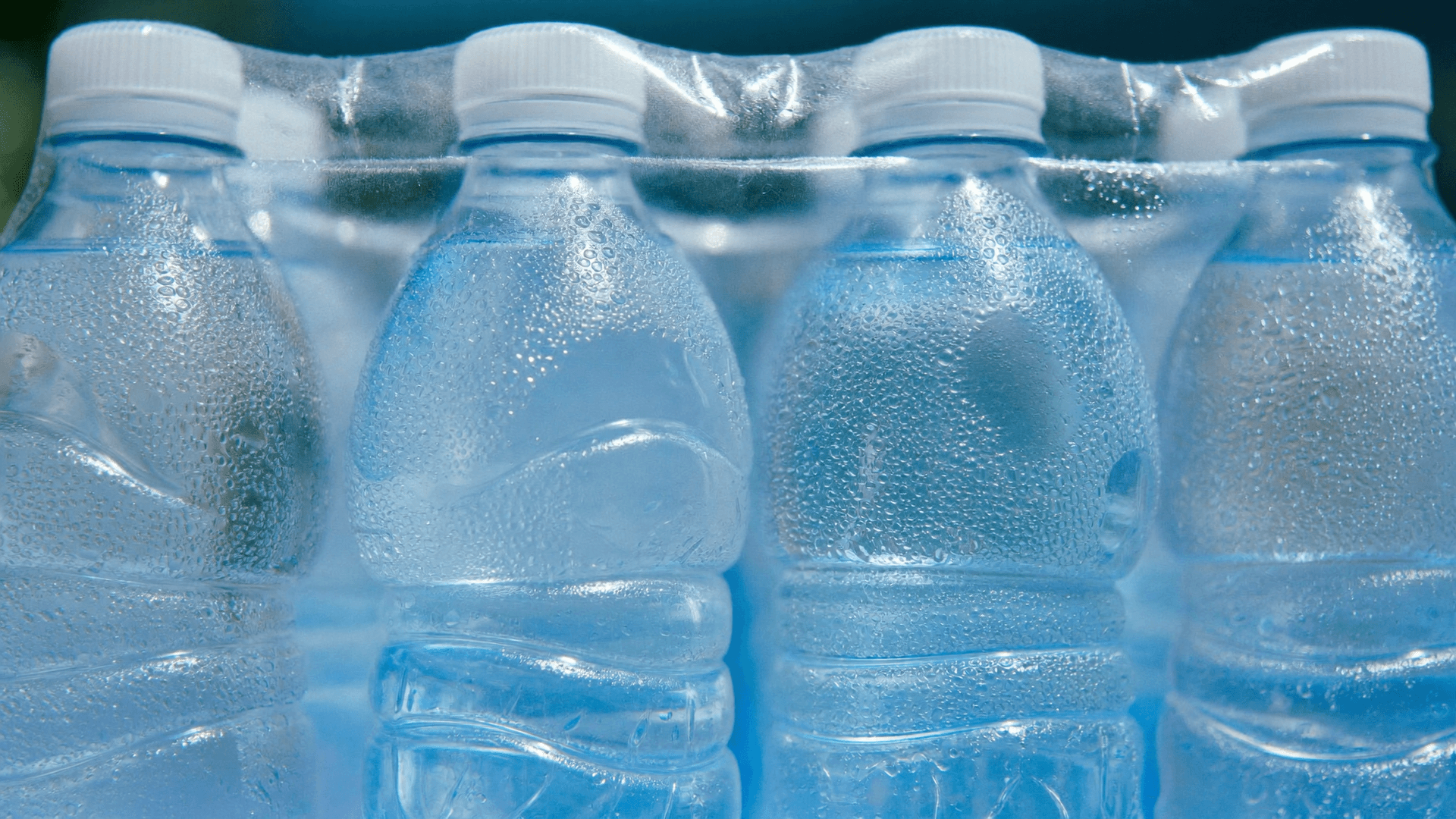 Packs de six bouteilles d'eau minérale dans un rayon de supermarché suisse, avec étiquette d'action et prix au litre